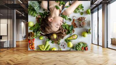 Beauty portrait of a woman surrounded by various healthy food lying on the floor. Healthy eating and sports lifestyle concept Wall mural