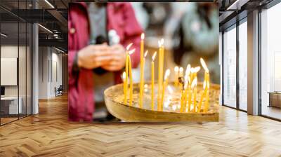 Burning candles with praying man on the background in the church Wall mural