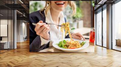 Businesswoman having lunch with pasta and fruit tea at the vegan restaurant on the green background Wall mural