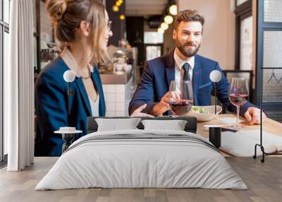 Caucasian business couple dressed strictly in the suits having discussion sitting together at the restaurant during the dinner Wall mural