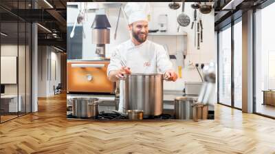 Chef cook in uniform cooking soup in the big cooker at the restaurant kitchen Wall mural