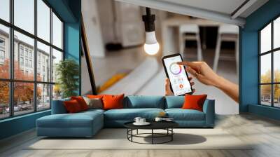 Controlling light bulb temperature and intensity with a smartphone application. Concept of a smart home and managing light with mobile devices Wall mural