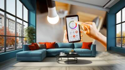 Controlling light bulb temperature and intensity with a smartphone application. Concept of a smart home and managing light with mobile devices Wall mural