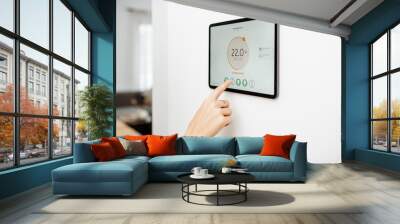 Controlling temperature in the living room with a digital touch screen panel installed on the wall. Concept of heating control in a smart home, close-up on a screen Wall mural