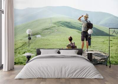 Couple enjoying beautiful landscape views, resting on the rock while traveling in the mountains during the summer time Wall mural