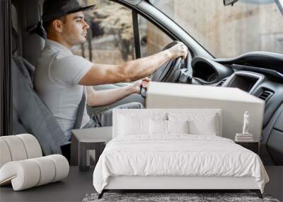 Delivery man driving cargo vehicle with parcels on the passenger seat, vehicle interior view on the boxes with blank space Wall mural