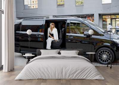 elegant business lady in white looks out of a minivan taxi. concept of business trips and transporta Wall mural