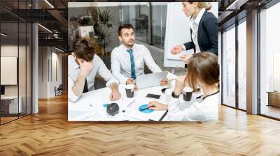 Female top manager or team leader quarreling at employees, dissatisfied with their work during a conference in the meeting room Wall mural