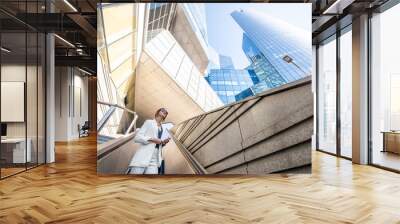 Geometrical view from below on the modern financial district with business woman going up on the escalator Wall mural