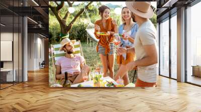 Group of a young friends having festive lunch, drinking wine in the beautifully decorated garden on a sunset Wall mural