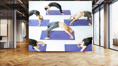 Group of athletic people keeping yoga pose during the training in the white studio Wall mural