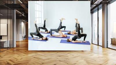 Group of athletic people keeping yoga pose during the training in the white studio Wall mural