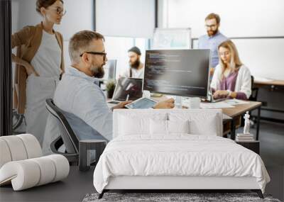 Group of diverse colleagues working on the computers in the modern office or coworking space, writing programming code Wall mural