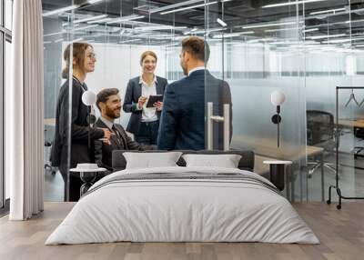 group of strictly dressed business people having a discussion, sitting at the workplace with a compu Wall mural