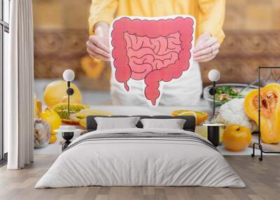 Holding bowel model with variety of healthy fresh food on the table. Concept of balanced nutrition for gut health Wall mural