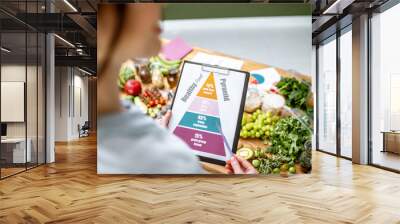 Holding schematic meal plan for diet with various healthy products on the background Wall mural