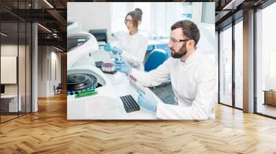 Laboratory assistants making analysis with test tubes and analyzer machines sitting at the modern laboratory Wall mural