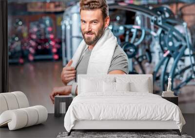 Lifestyle portrait of handsome muscular man looking at the smart watch after the exercise in the sport gym Wall mural