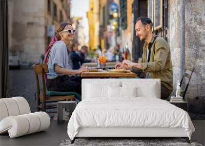 Man and woman eating italian pasta and drinking wine at restaurant on the street in Rome. Concept of Italian gastronomy and travel. Italian couple having lunch together Wall mural