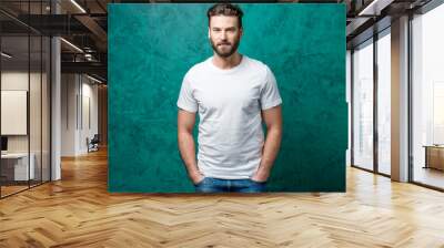 Man in the white t-shirt with space to copy paste standing on the green wall background. Wall mural