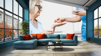 Nurse giving some medicine for a senior woman sitting on the couch, taking care of elder patients in the hospital Wall mural