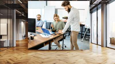 Office workers eating salad while sitting on the working place during a lunch time without leaving the office. Concept of healthy takeaway food on the work Wall mural