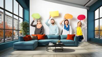 People in casual clothes holding colorful bubbles sitting in a row on the white wall background Wall mural