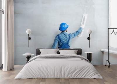 Plasterer in blue working uniform plastering the wall indoors Wall mural