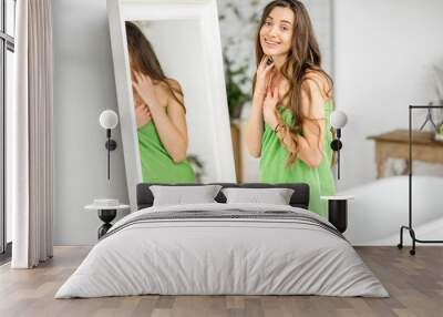 Portrait of a beautiful woman in the green towel standing near the mirror in the bathroom Wall mural