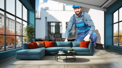 Portrait of a builder in uniform laying paving tiles on the construction site with white houses on the background Wall mural