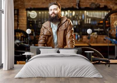 Portrait of a handsome bearded man as bicycle store owner or manager standing with laptop at the bicycle workshop Wall mural