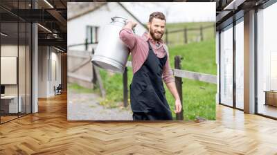 Portrait of a handsome milkman in apron walking with milk container outdoors on the rural scene background Wall mural