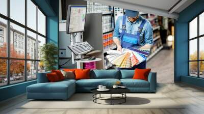 Portrait of a handsome workman with color swatches near the equipment for coloring in the building shop Wall mural