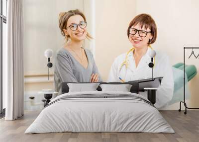 Portrait of a smiling young woman patient and senior gynecologist during the consultation in the office Wall mural