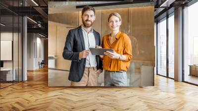 Portrait of a two colleagues standing together with digital tablet in creative studio. Work in marketing agency or design studio concept Wall mural