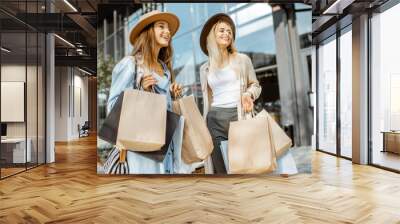 Portrait of a two happy women with shopping bags, standing together in front of the shopping mall Wall mural