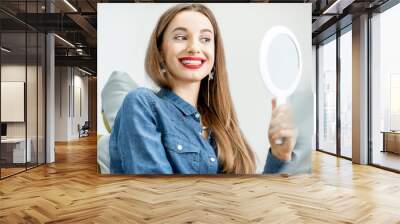 Portrait of a young beautiful woman looking on the mirror enjoying her beautiful smile in the dental office Wall mural