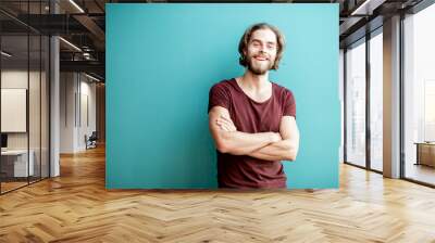 Portrait of a young caucasian bearded man with long hair dressed in t-shirt on the colorful background Wall mural