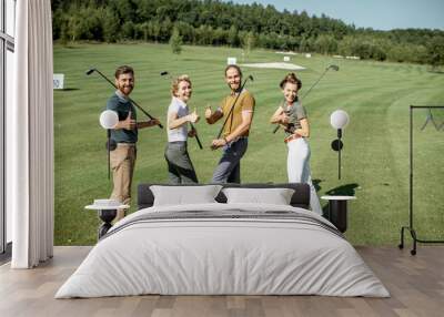 Portrait of a young group of friends walking with golf equipment on the beautiful golf course during a game on a sunny day Wall mural