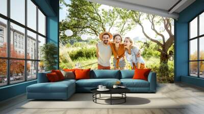 Portrait of a young happy friends hugging together in the garden or backyard during the festive lunch or party on a sunny day Wall mural