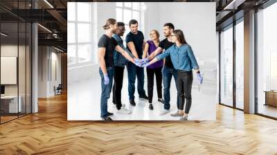 Portrait of a young team of students or coworkers touching hands together after the first aid training in the white classroom Wall mural