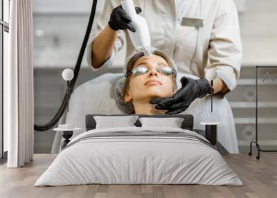 Portrait of a young woman during a facial rejuvenation treatment at medical SPA. LaseMD procedure concept Wall mural