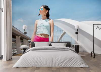 Portrait of a young woman in sportswear standing on the modern white bridge in Lyon city Wall mural