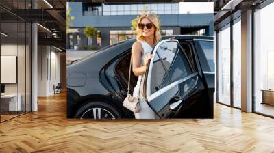 portrait of an elegant business lady in white casual getting out of a luxury black car. concept of b Wall mural