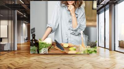 Pretty woman with green ingredients thinking about cooking healthy food on the kitchen. Healthy and wellness concept. High quality photo Wall mural