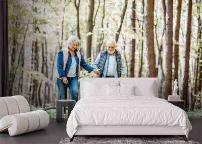 Senior couple walking together in the forest, enjoying nature and free time on their retirement Wall mural