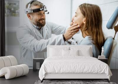 Senior otolaryngologist examining nose of a young patient during a medical examination in the ENT office Wall mural