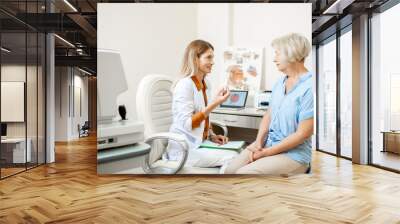 Senior woman patient talking with female ophthalmologist during a medical consultation at the ophthalmologic office. Doctor offering eye medcine for a patient Wall mural