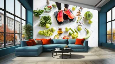 Sports woman weighing on the scales with healthy food around. Weight loss, healthy food and sports lifestyle concept Wall mural