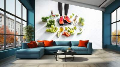 Sports woman weighing on the scales with healthy food around. Weight loss, healthy food and sports lifestyle concept Wall mural